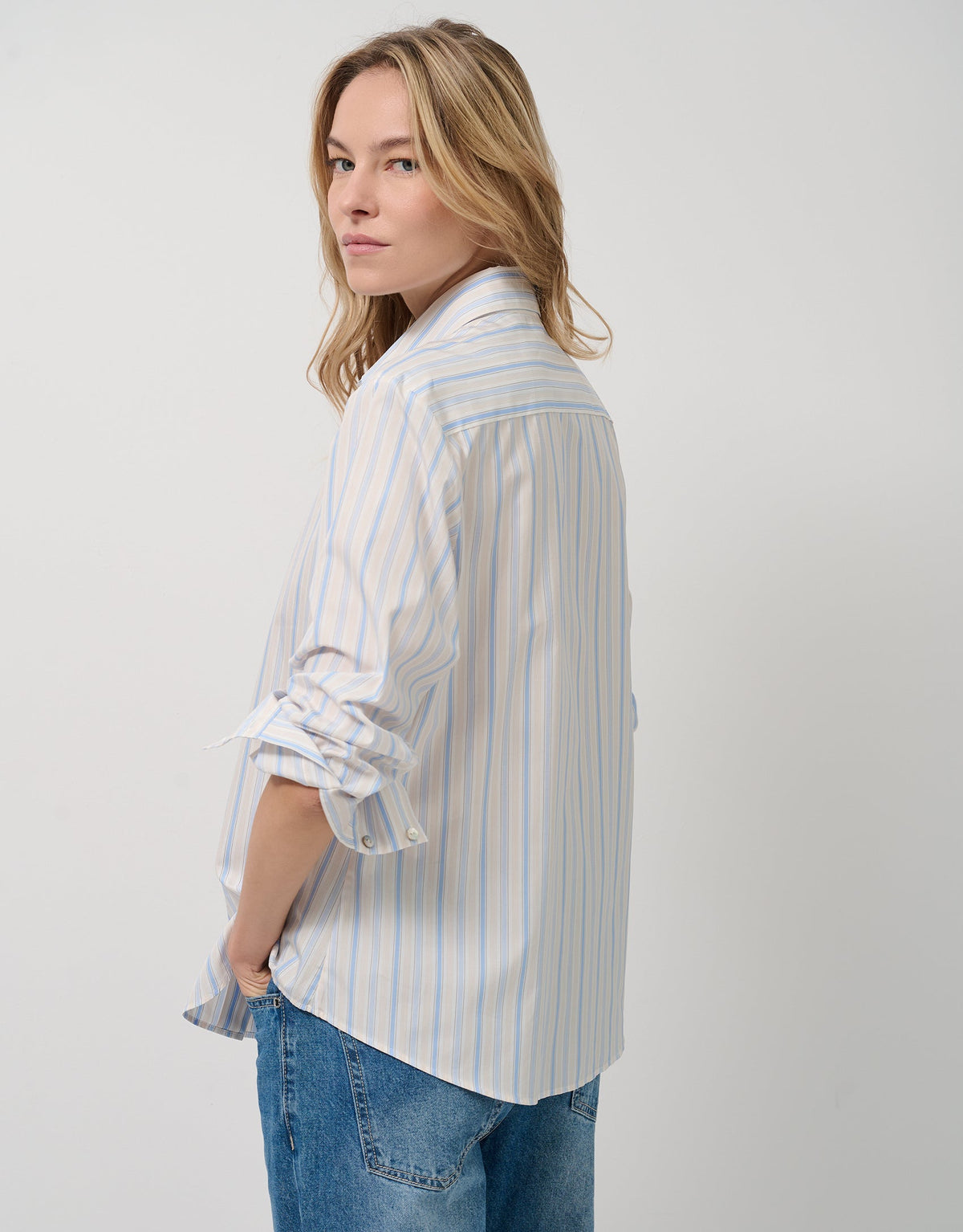Woman wearing a striped shirt and jeans on a plain background