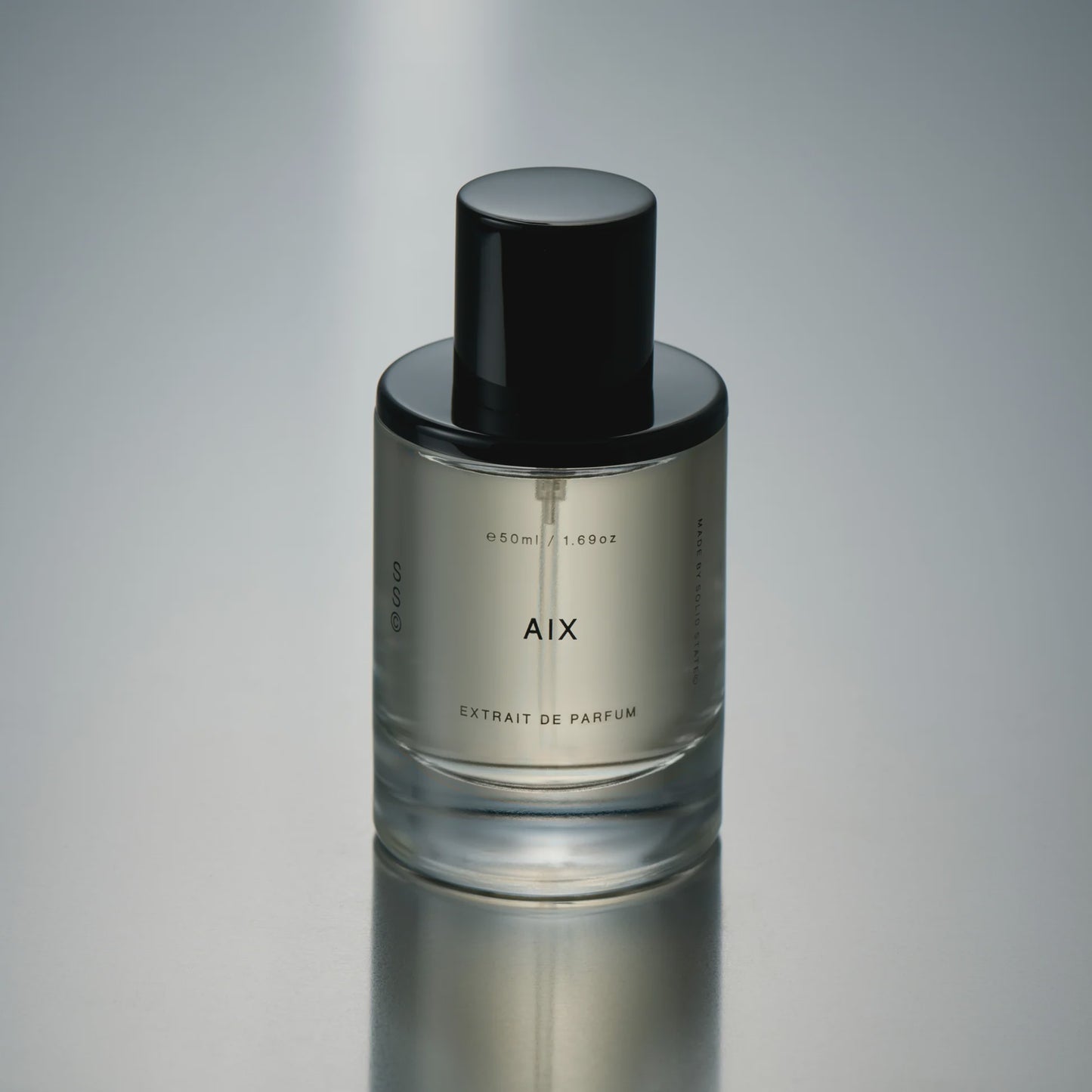 Perfume bottle labeled 'AIX' on a reflective gray surface