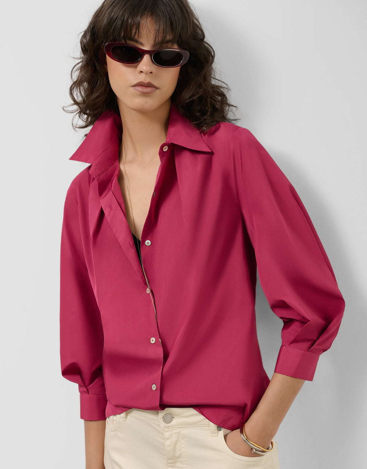 Woman wearing a bright pink blouse with a plain background