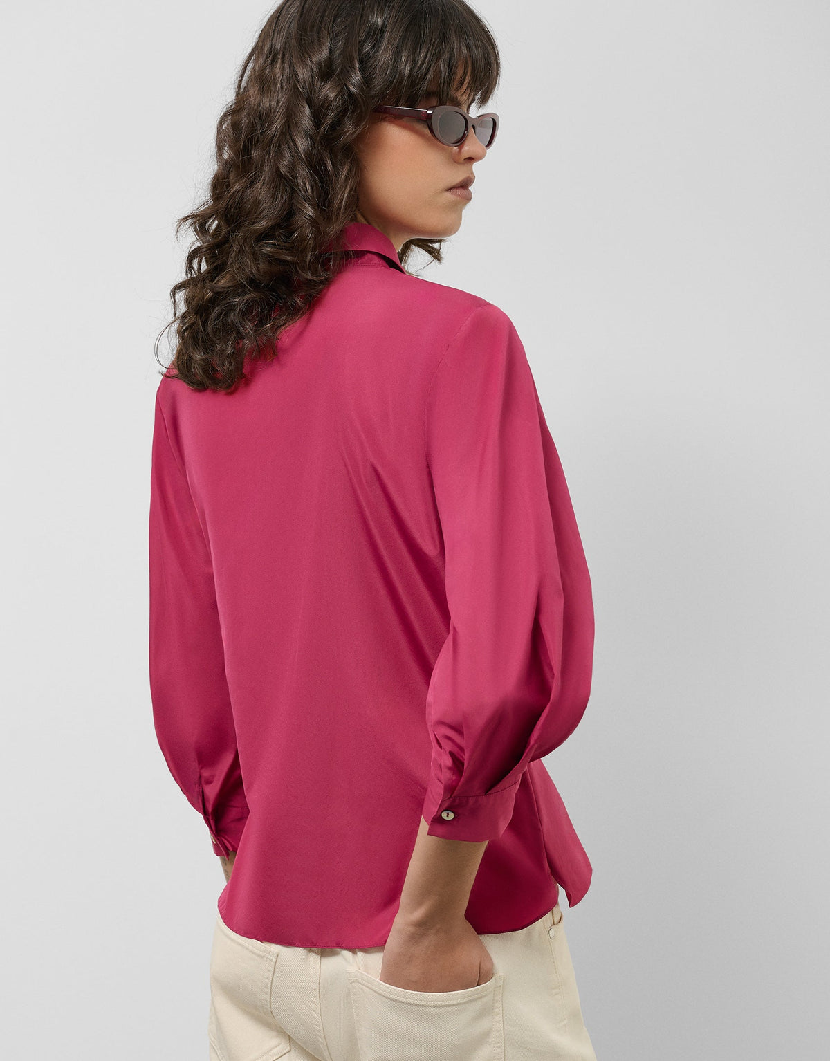 Person wearing a pink blouse with long sleeves on a plain background