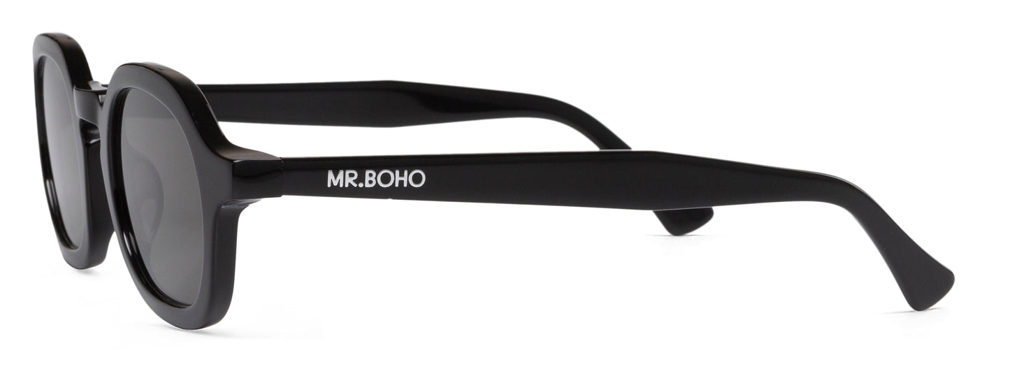 A pair of black-framed oval sunglasses with dark lenses side view with mr boho logo