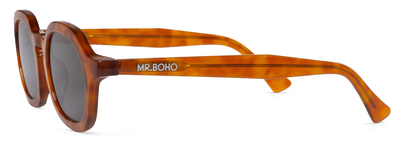 A pair of brown-framed oval sunglasses with dark lenses side view with mr boho logo