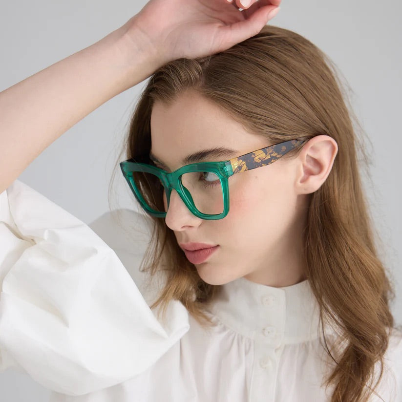 Woman wearing green square framed glasses with dark patterned arms and clear lenses