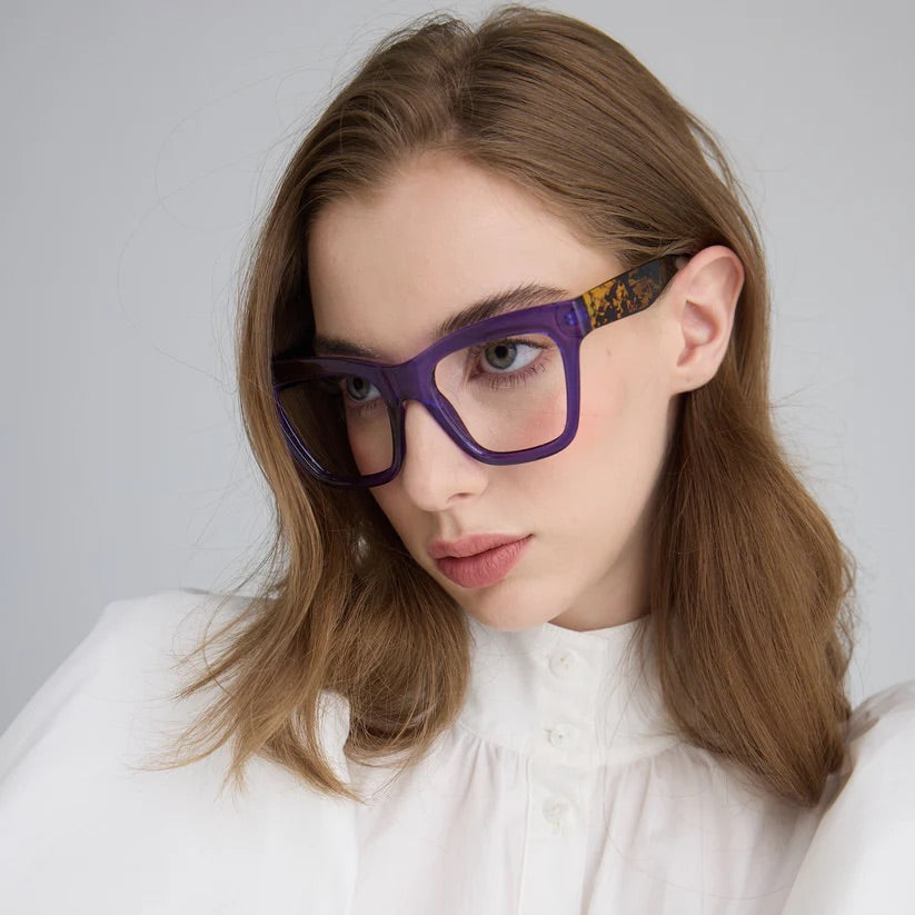 Woman wearing purple square framed glasses with dark patterned arms and clear lenses