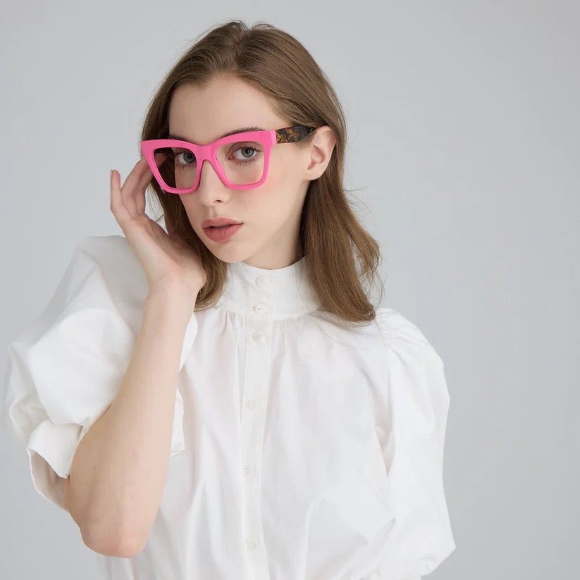 Woman wearing pink square framed glasses with dark patterned arms and clear lenses