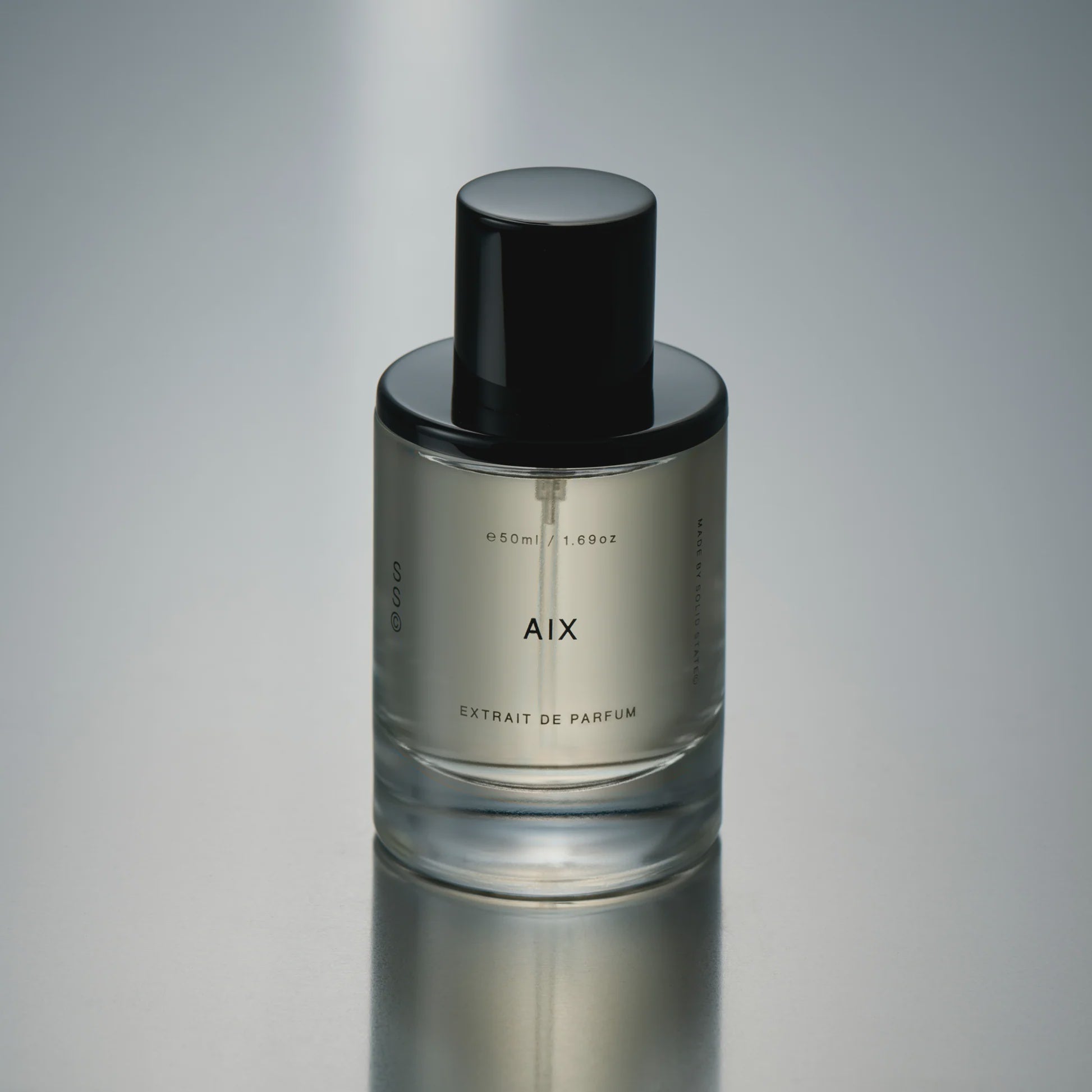 Perfume bottle labeled 'AIX' on a reflective gray surface