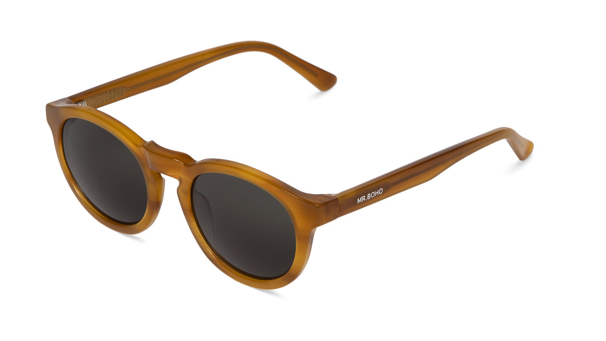 A pair of Jordaan sunglasses with a round shape and wooden appearance frame, dark polarized lenses, and metal hinges.
